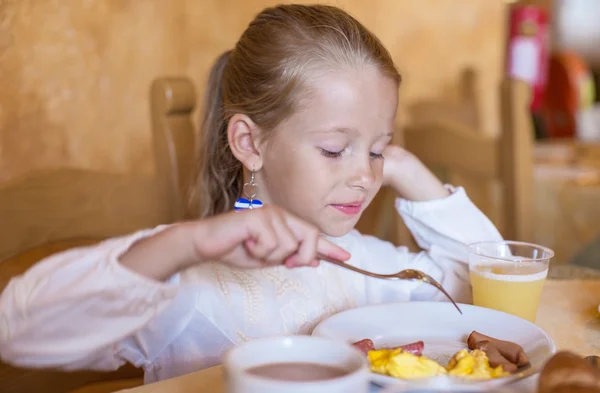 Adorable little girl having breakfast at indoor cafe — Stock Photo, Image