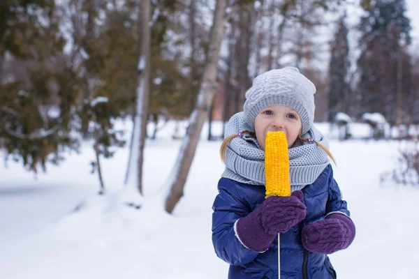 Niña comiendo maíz al aire libre en el día de invierno — Foto de Stock