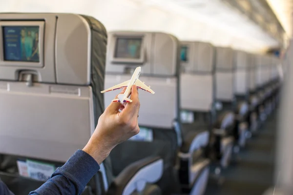 Nahaufnahme Hand hält ein Flugzeugmodell in einem großen Flugzeug — Stockfoto
