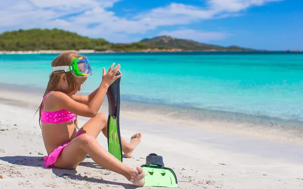 Little girl with flippers and goggles for snorkling on white beach — Stock Photo, Image