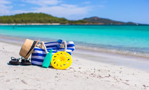 Полосатый мешок, соломенная шляпа, солнцезащитный крем и полотенце на пляже — стоковое фото