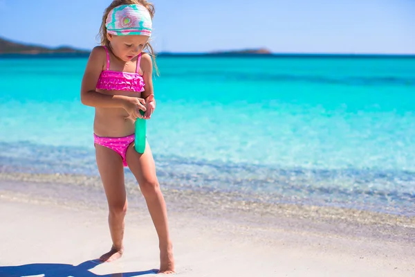 Little adorable girl in swimsuit with suntan lotion bottle — Stock Photo, Image