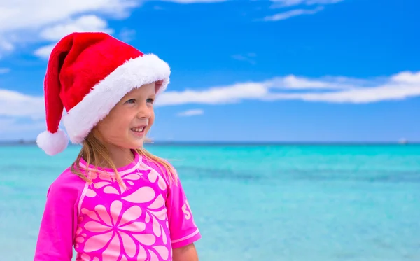 Urocze dziewczynki santa kapeluszu na tropikalnej plaży — Zdjęcie stockowe