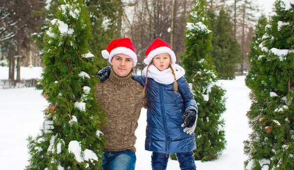 Happy father and little girl in Santa hats with christmas tree outdoor Royalty Free Stock Images