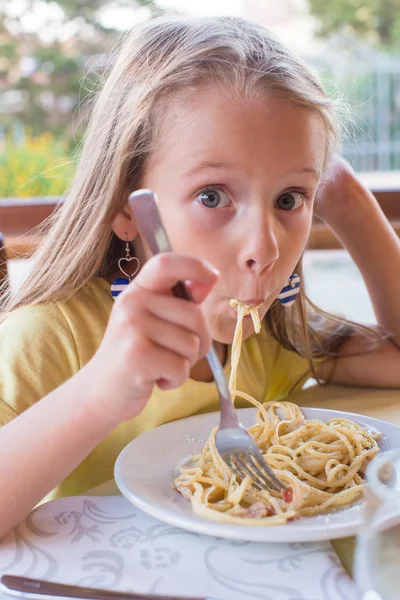 Entzückendes kleines Mädchen, das Spaghetti im Freien isst Stockbild