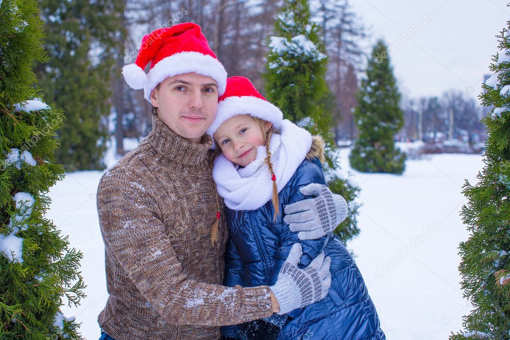 Happy family in Santa hats with christmas tree outdoor
