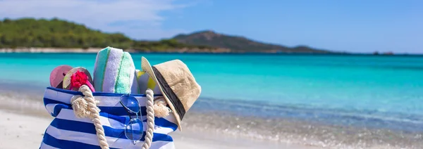 Blue bag, straw hat, flip flops and towel on white beach — Stock Photo, Image