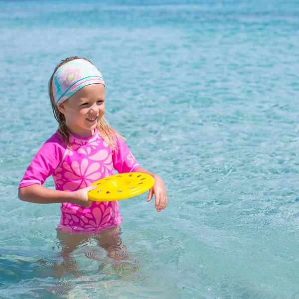 Liten flicka spela frisbee under tropiska semester i havet — Stockfoto