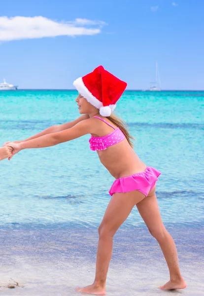 Little adorable girl in red Santa hat at tropical beach — Stock Photo, Image