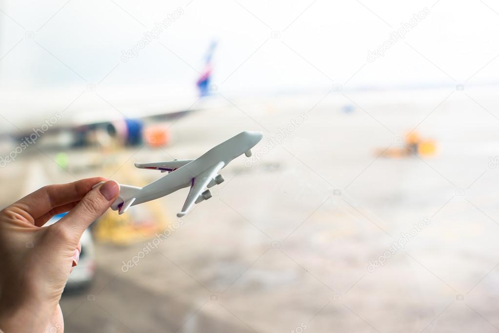 Close up hand holding an airplane model at airport
