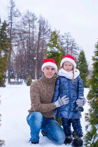 Feliz padre y niño en sombreros de Santa con árbol de Navidad al aire libre — Foto de Stock