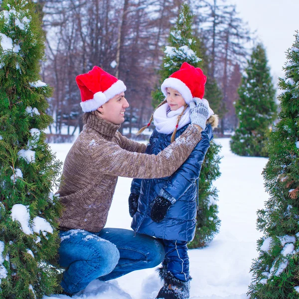 Família feliz em chapéus de Santa com árvore de Natal ao ar livre — Fotografia de Stock