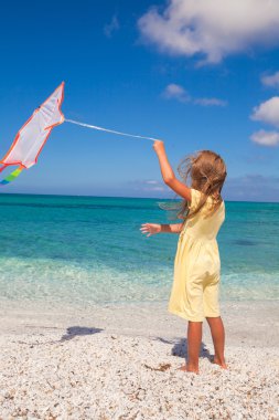 Tropikal plaj tatil sırasında uçurtma uçan ile oynarken mutlu küçük kız