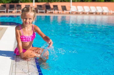 Kameraya bakarak yüzme havuzunda mutlu küçük kız