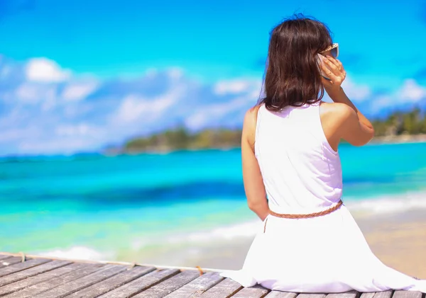 Young woman talking on phone during tropical beach vacation — Stock Photo, Image