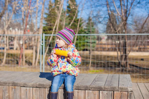 Little adorable girl eating corn outdoors — Stock Photo, Image
