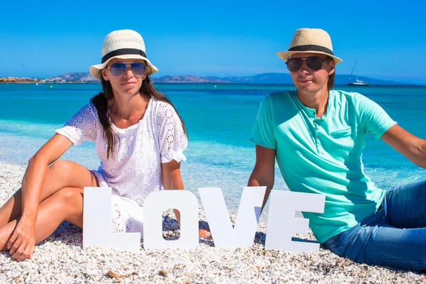 Giovane famiglia seduta sulla spiaggia con la parola Amore — Foto Stock