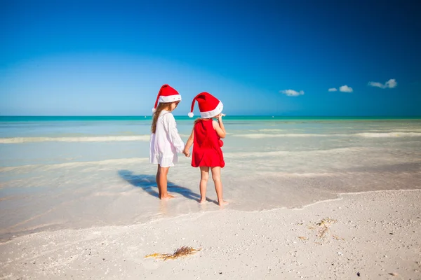 Kleine entzückende Mädchen in Weihnachtsmützen während des Strandurlaubs — Stockfoto