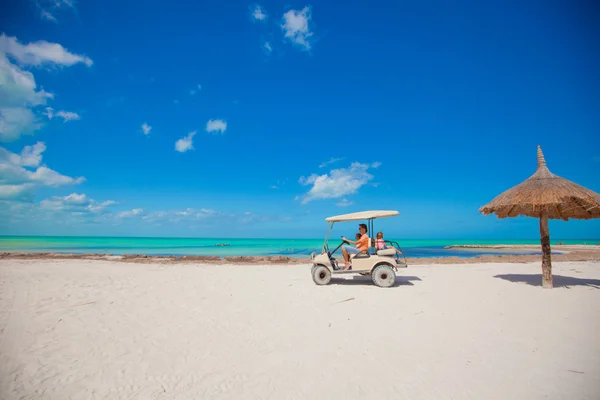 Dad and his little girls driving golf cart on tropical beach — Stock Photo, Image