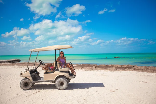 Petites filles et leur mère conduisant une voiturette de golf à la plage tropicale — Photo