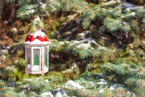 Christmas lantern with snowfall hanging on a fir branch