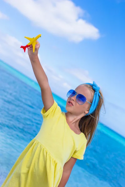 Gelukkig meisje met speelgoed vliegtuig op witte zandstrand — Stockfoto