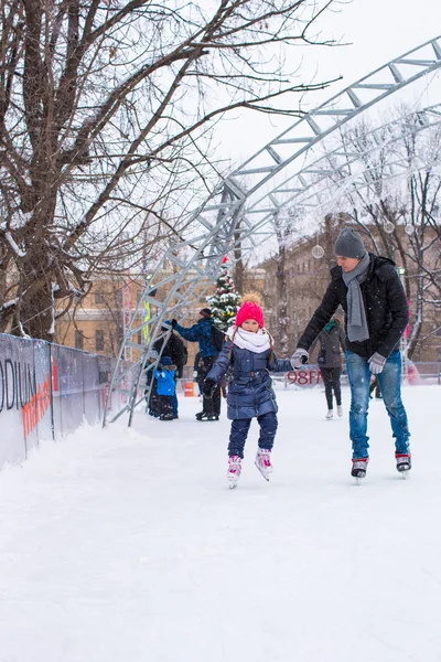 Adorable niña y padre feliz en pista de patinaje al aire libre —  Fotos de Stock