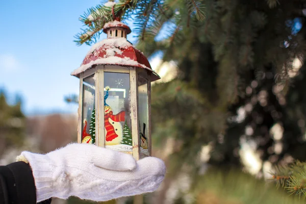 Beautiful red vintage Christmas lantern on warm mittens outdoors — Stock Photo, Image