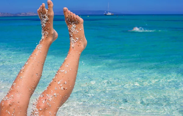 Closeup of female legs background of the turquoise sea — Stock Photo, Image