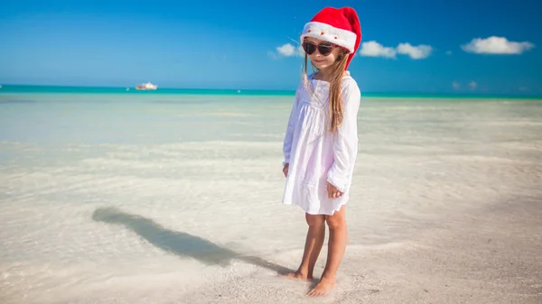 Piccola adorabile ragazza in rosso cappello di Babbo Natale sulla spiaggia tropicale — Foto Stock