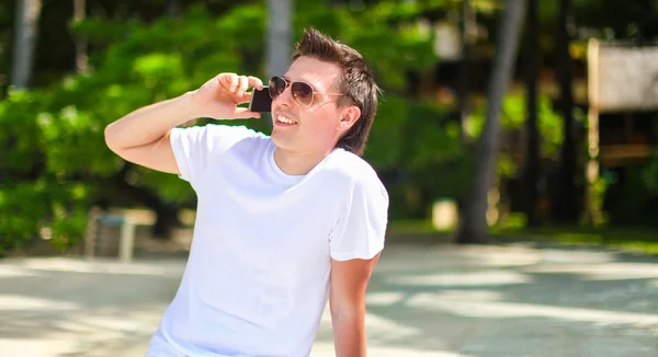 Young man talking on phone during tropical beach vacation — Stock Photo, Image