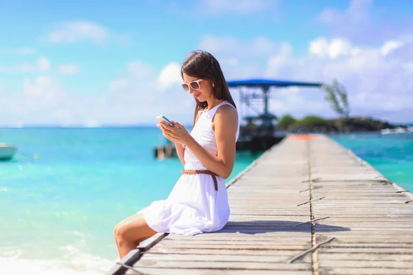 Młoda kobieta rozmawia telefon podczas wakacji na tropikalnej plaży — Zdjęcie stockowe