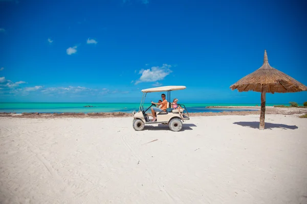 Papa und seine kleinen Mädchen fahren Golfcart am tropischen Strand — Stockfoto