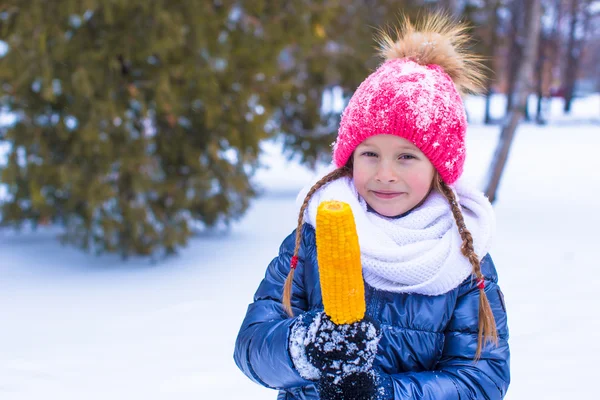 Niña adorable con maíz dulce en el parque de invierno — Foto de Stock