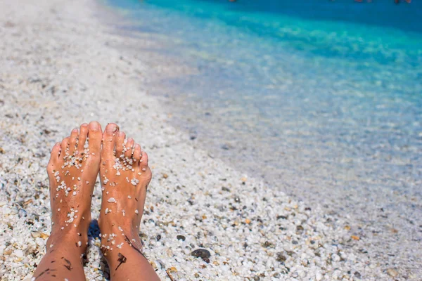 女性的腿，带白色的沙质海滩上的卵石 — 图库照片