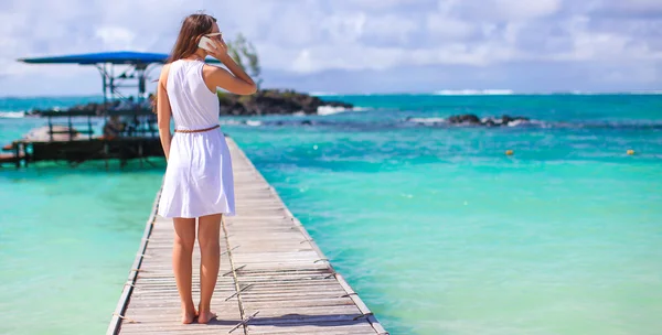Młoda kobieta rozmawia telefon podczas wakacji na tropikalnej plaży — Zdjęcie stockowe