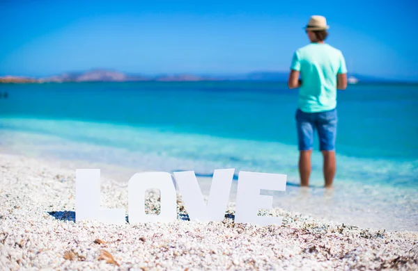 Junger Mann am Strand mit dem Wort Liebe — Stockfoto