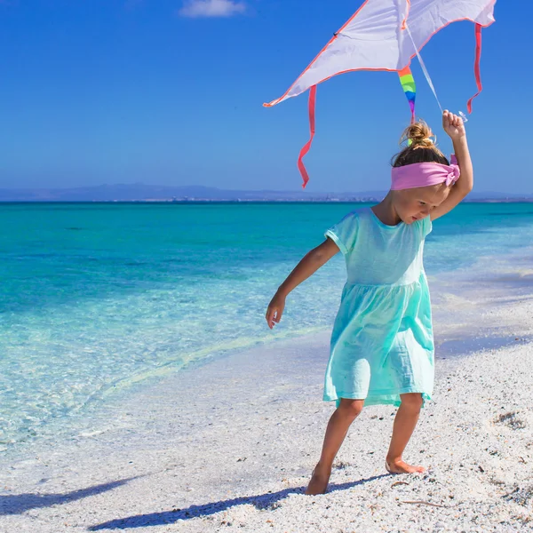Liten glad tjej leker med flyga drake på tropical beach — Stockfoto