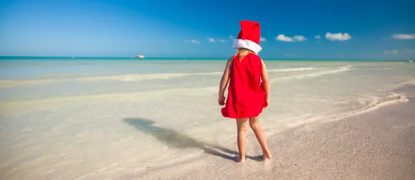 Little adorable girl in red Santa hat at tropical beach — Stock Photo, Image