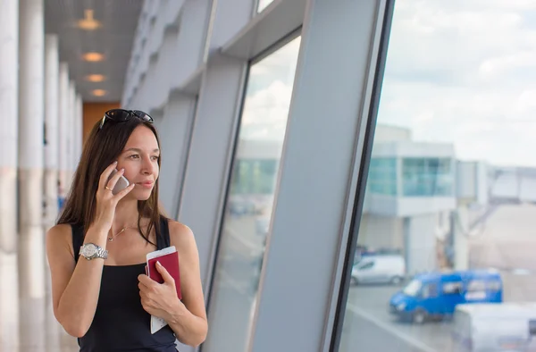 Женщина разговаривает по мобильному телефону с посадочным паспортом в аэропорту — стоковое фото