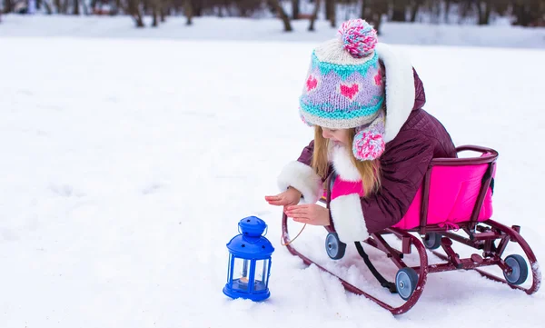 Liten flicka värmer händerna på ljus i lyktan utomhus — Stockfoto