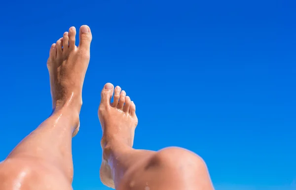 Närbild av kvinnliga ben bakgrunden av det turkosa havet — Stockfoto