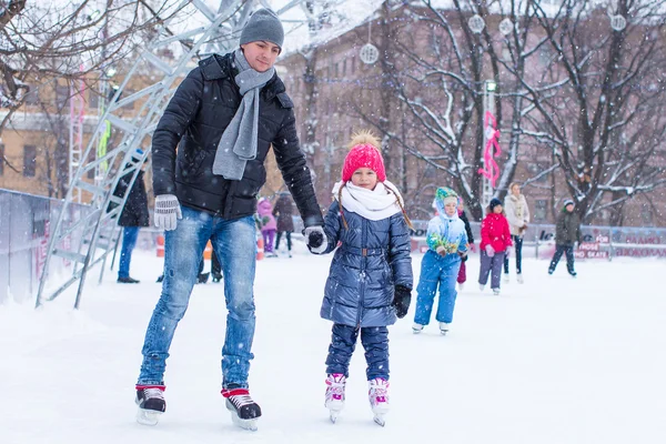 Adorable little girl and happy dad on skating rink outdoor — Stock Photo, Image