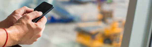 Close up mans hands using cellphone inside airport — Stock Photo, Image