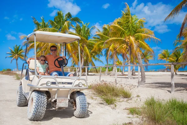 Dziewczynka z wózkiem golfowym ojca na tropikalnej plaży — Zdjęcie stockowe