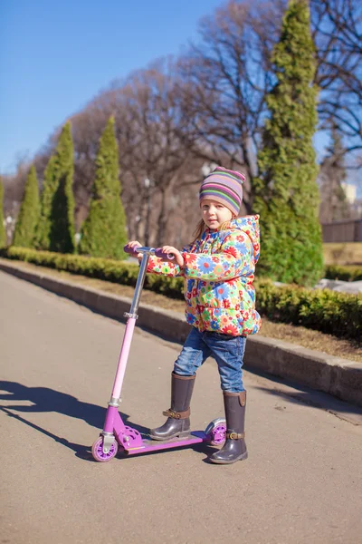 Bedårande liten flicka ha kul på skoter utomhus — Stockfoto