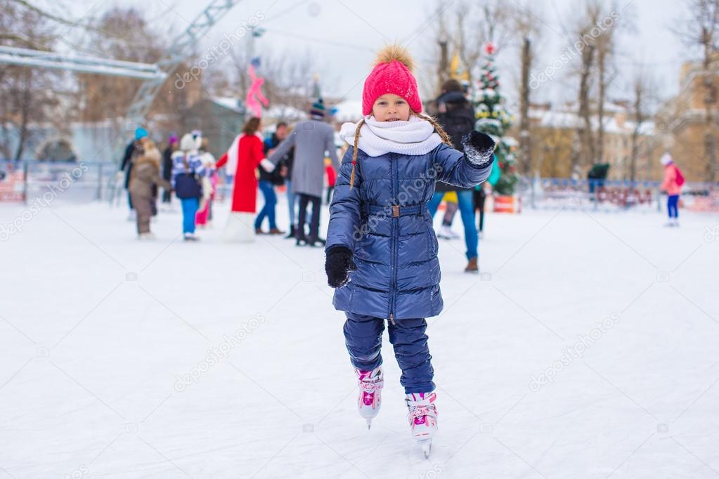 Cute little girl skating on the ice rink outdoors