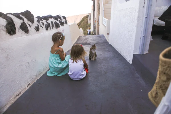 Little adorable girls sitting near cat in Greek village, Emporio, Santorini — Stock Photo, Image