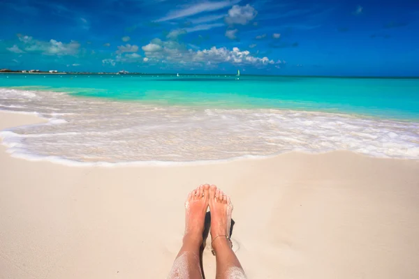 Zblízka ženské nohy na bílé písečné pláži — Stock fotografie