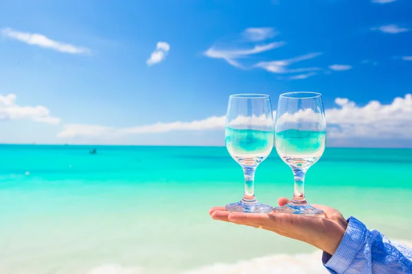 Primer plano de las gafas de vino en la mano en la playa de arena blanca — Foto de Stock